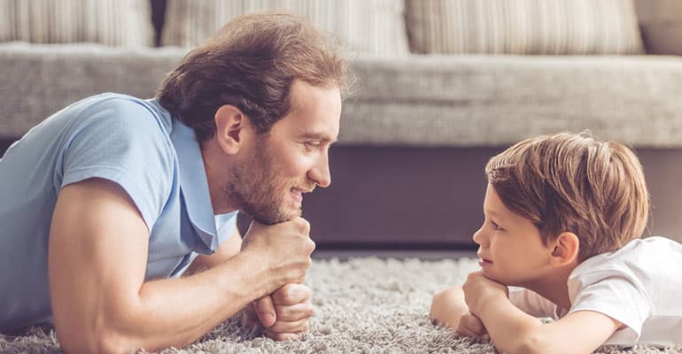 Father and child lie on carpet