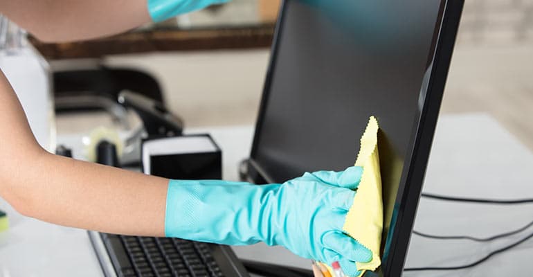 Cleaner wipes down computer monitor